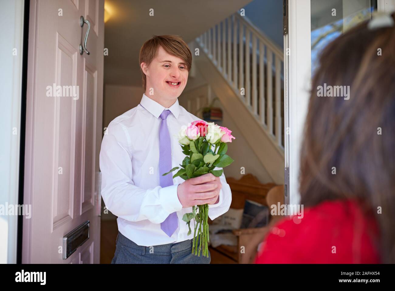 Amare i giovani la sindrome di Downs giovane davanti alla porta di casa con l'uomo che donna fiori Foto Stock