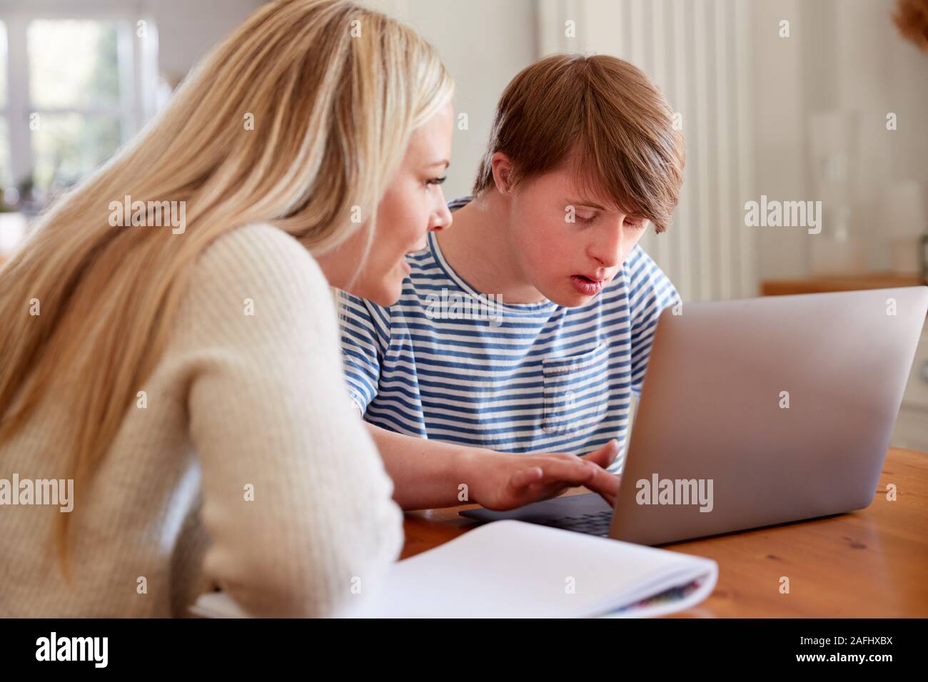 La sindrome di Down Uomo seduto con il Tutor di casa utilizzando computer portatile per la lezione a casa Foto Stock