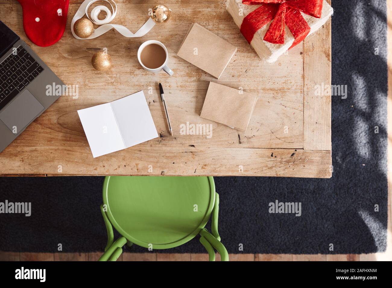Scatto dall'alto guardando verso il basso sullo sbozzato Scheda di Natale e regali avvolti indossando sul tavolo Foto Stock