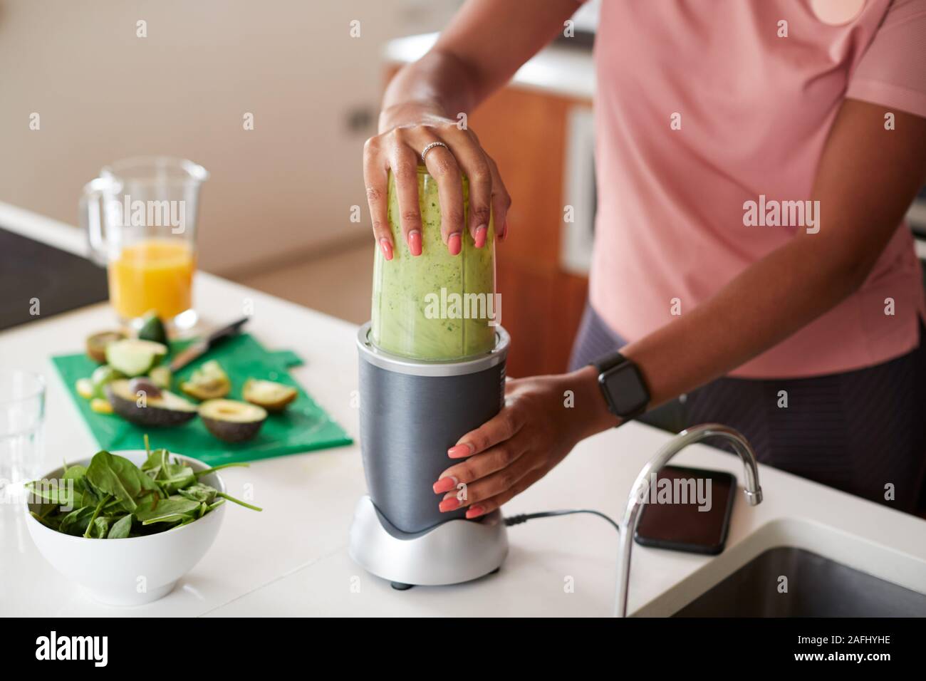 Close up della donna che fa un succo sano e drink con ingredienti freschi in spremiagrumi elettrico dopo l'esercizio Foto Stock