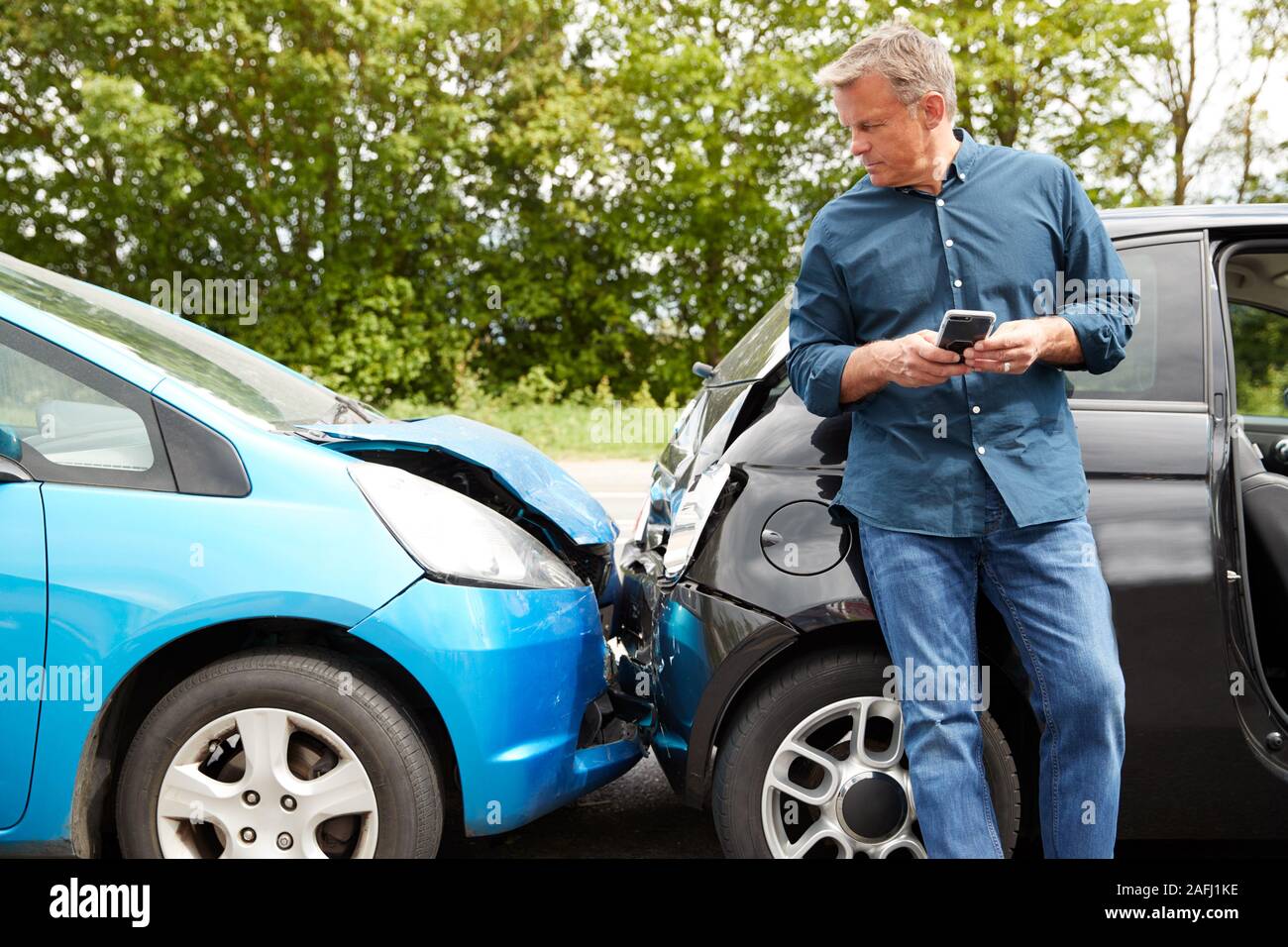 Maschio maturo automobilista coinvolto in incidente di auto chiamando compagnia di assicurazione o servizio di recupero Foto Stock