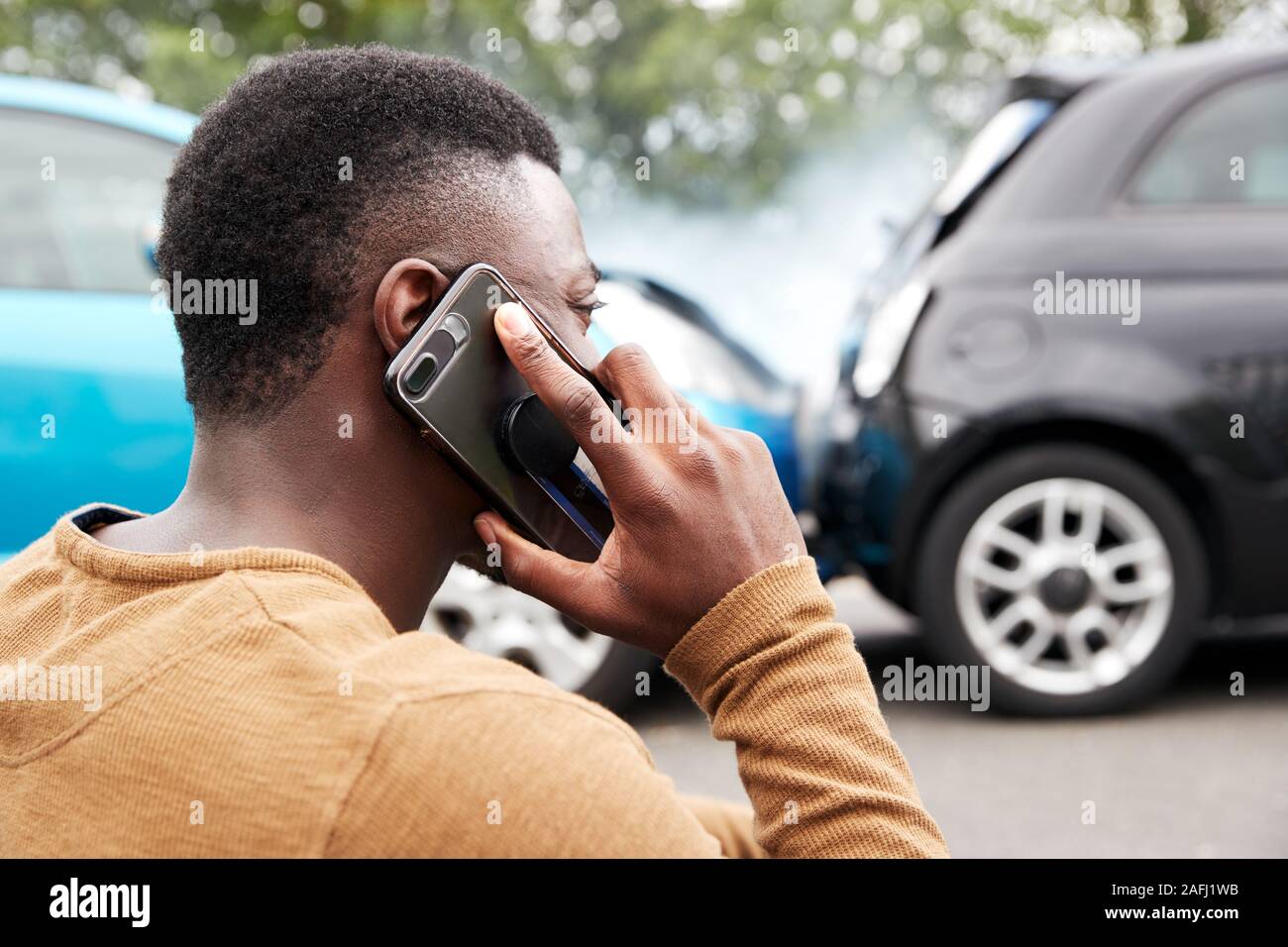 Automobilista maschio coinvolto in incidente di auto chiamando compagnia di assicurazione o servizio di recupero Foto Stock