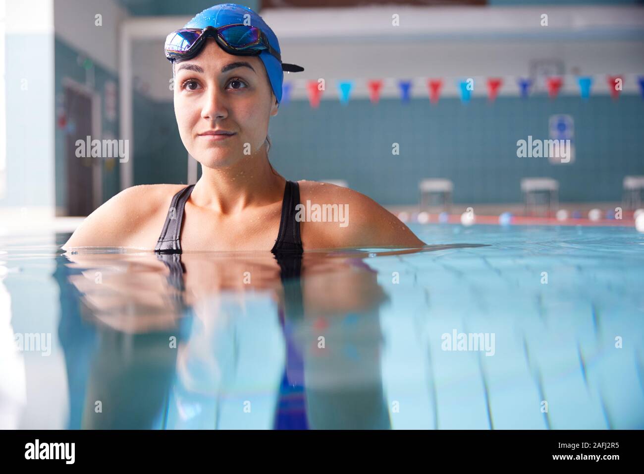 Nuotatore femmina indossando un cappello e occhiali formazione In Piscina Foto Stock
