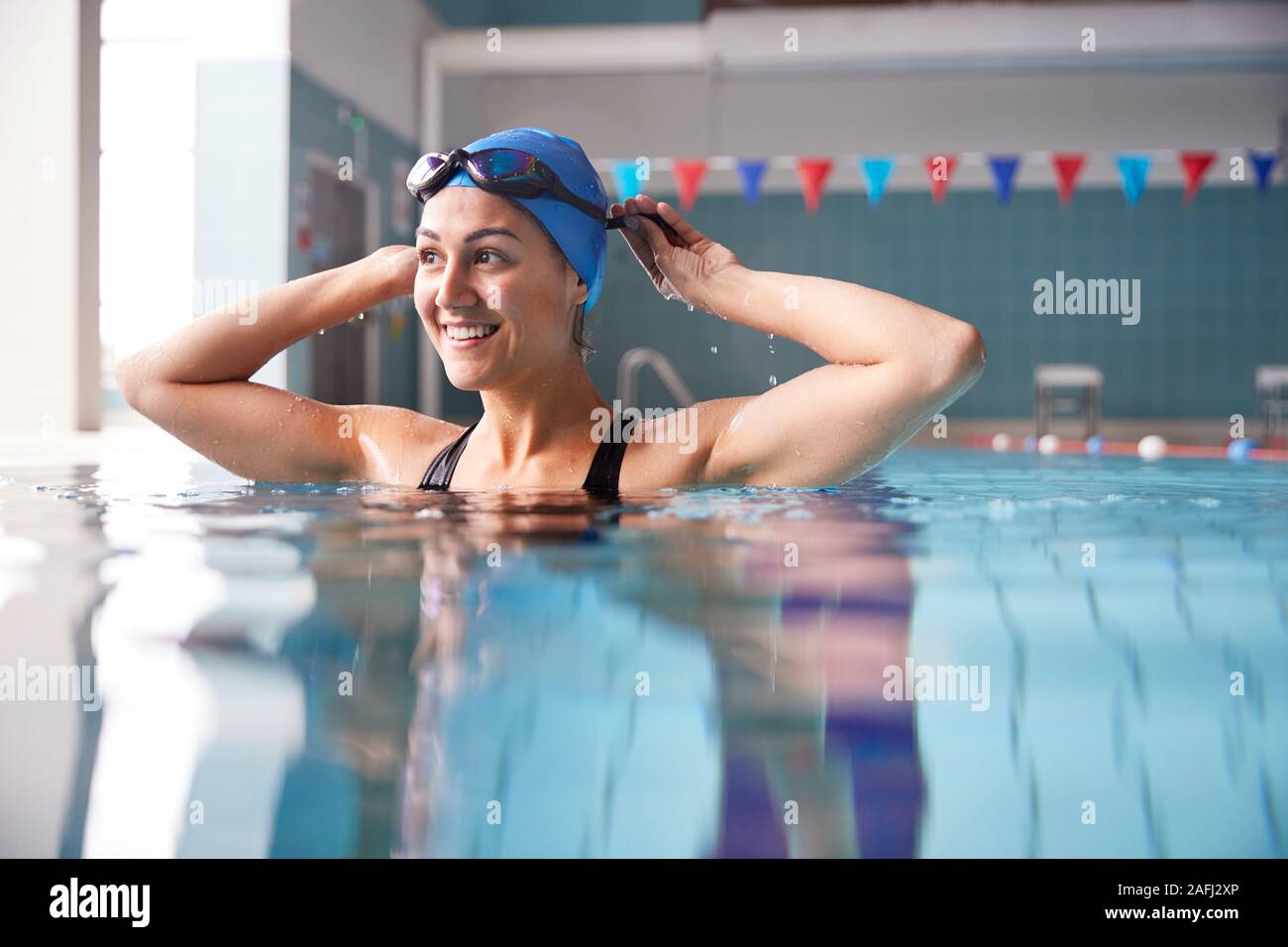 Nuotatore femmina indossando un cappello e occhiali formazione In Piscina Foto Stock