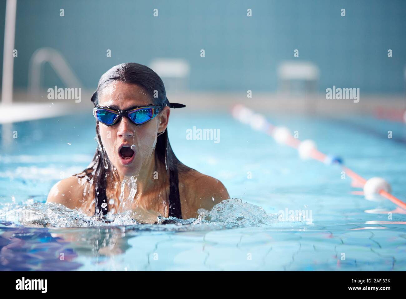 Nuotatore femmina che indossa gli occhiali di protezione formazione In Piscina Foto Stock