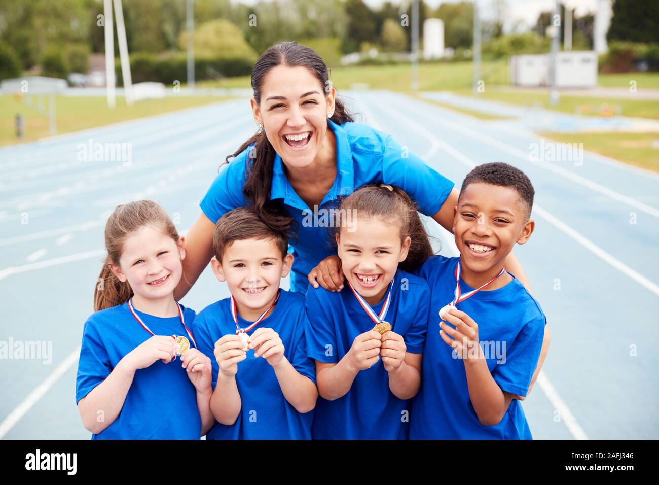 Ritratto di bambini con pullman femmina di mostrare a tutti i vincitori di medaglie sulla giornata di sport Foto Stock