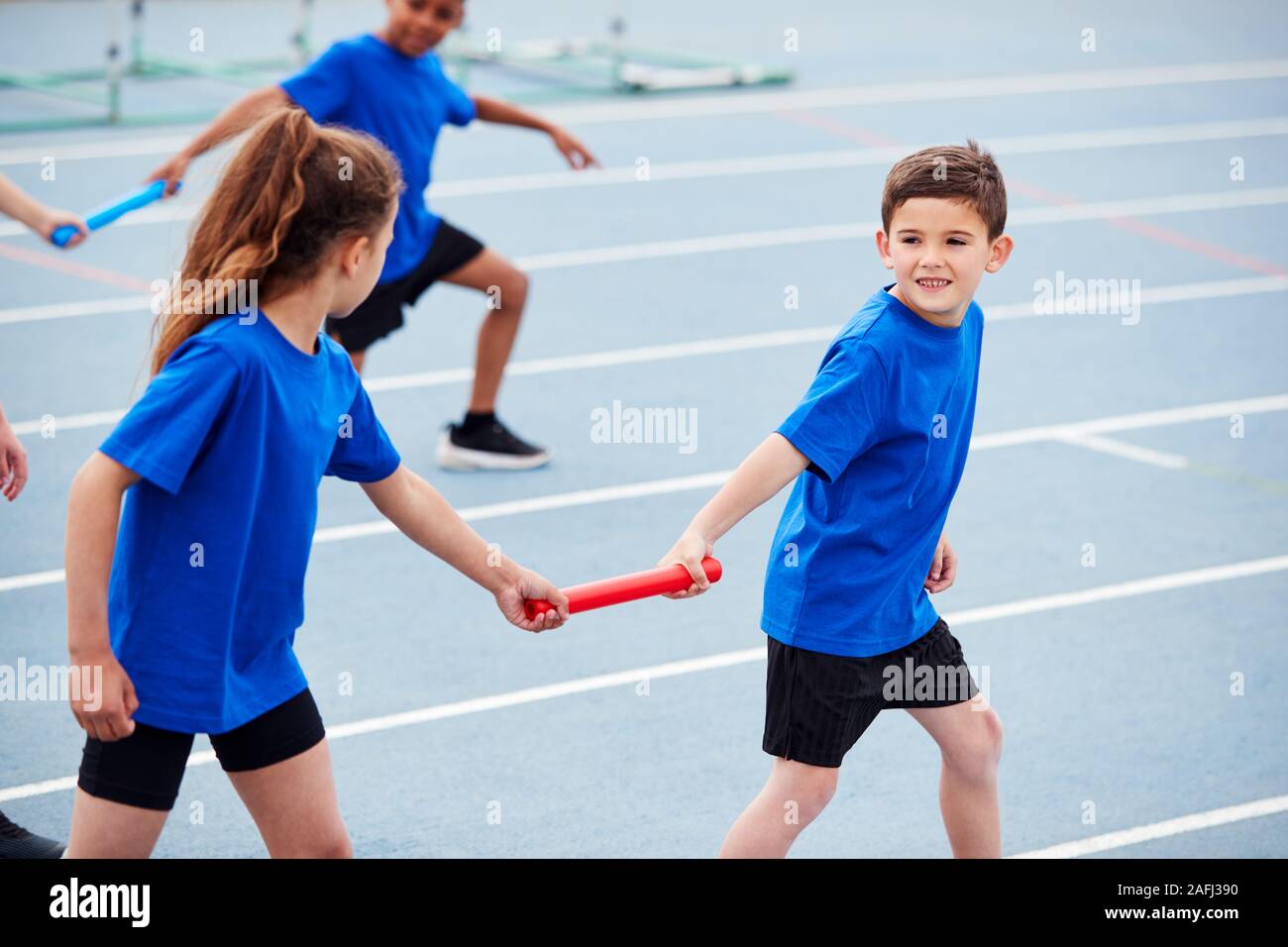 I bambini in atletica Team concorrenti in gara relè sulla giornata di sport Foto Stock