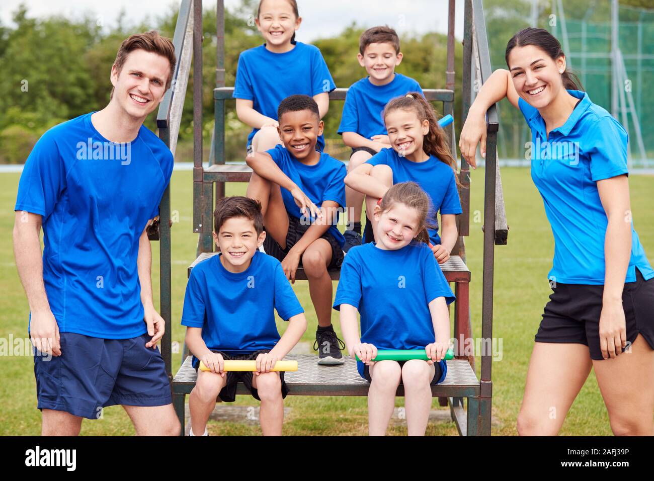 Ritratto di bambini con maschio e femmina allenatori Preparazione per la Staffetta sulla giornata di sport Foto Stock