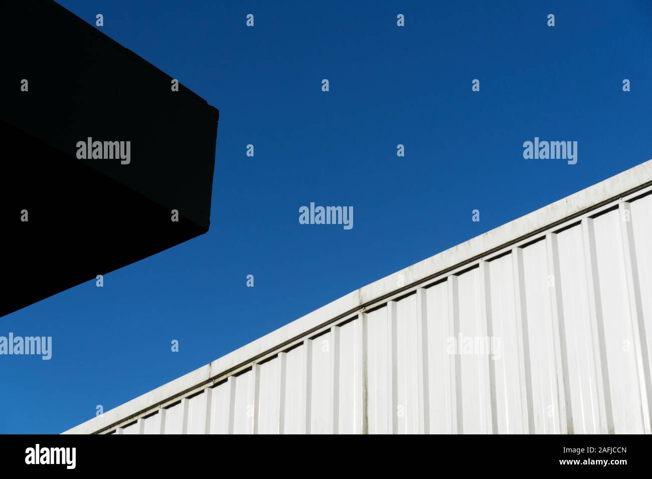 Bianco architettura di metallo con un luminoso cielo blu e parte del tetto e moderno edificio di colore nero lo sfondo astratto Foto Stock