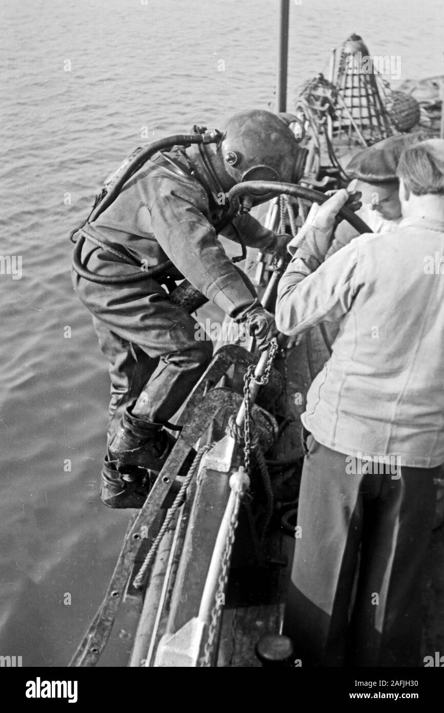 Ein Bojentaucher geht ins Wasser im Hafen von Emden, Niedersachsen, Deutschland 1950. Un subacqueo per arrivare in acqua per controllare le boe a Emden Harbour, Bassa Sassonia, Germania 1950. Foto Stock