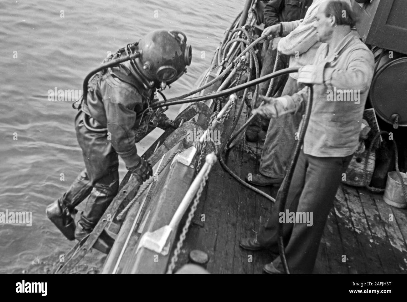 Ein Bojentaucher geht ins Wasser im Hafen von Emden, Niedersachsen, Deutschland 1950. Un subacqueo per arrivare in acqua per controllare le boe a Emden Harbour, Bassa Sassonia, Germania 1950. Foto Stock