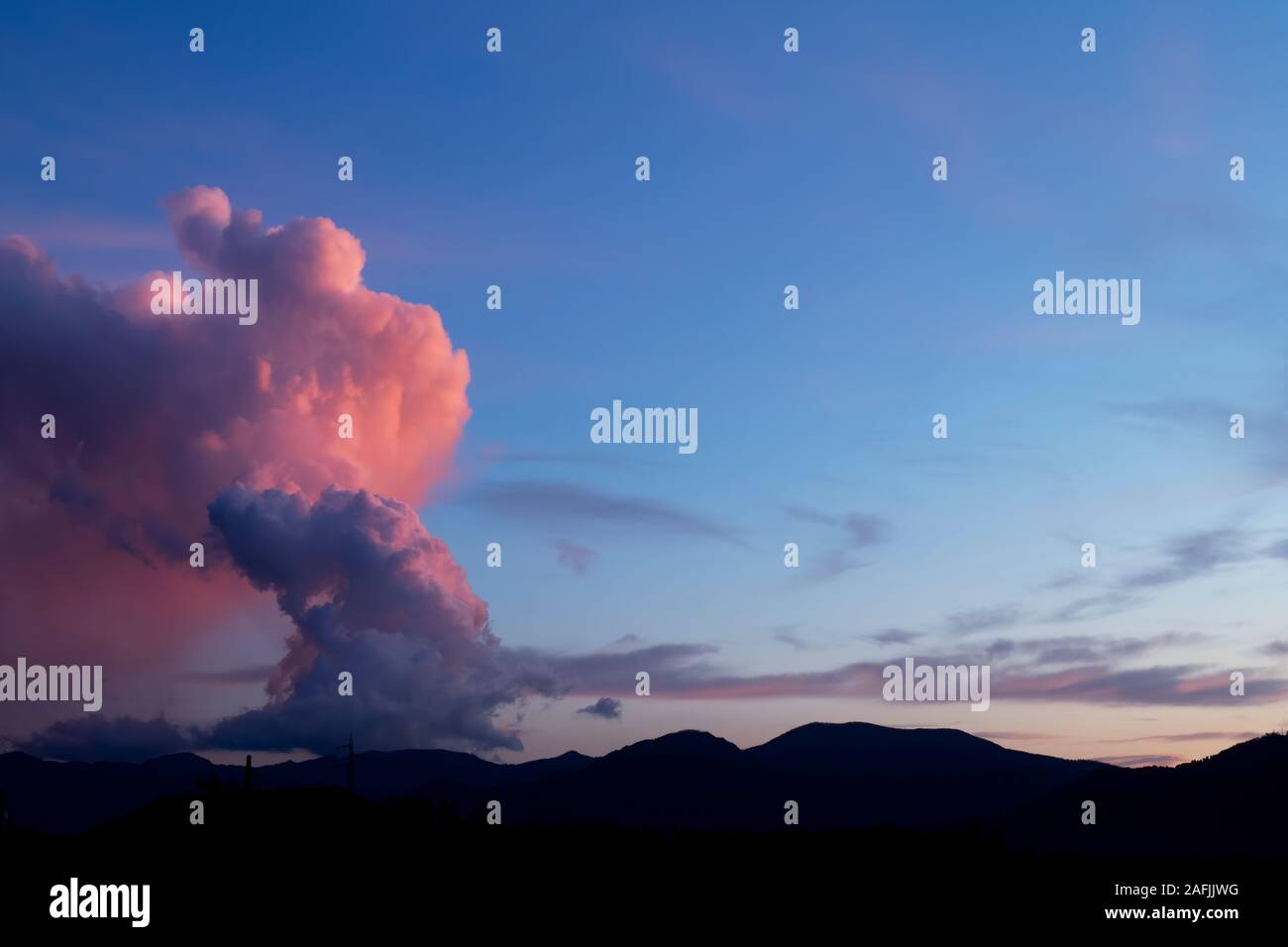 Cumulonimbus, grandinata nube su Lunigiana, Italia. Dicembre 2019. Colonna torreggiante al tramonto con il cielo rosso. Foto Stock