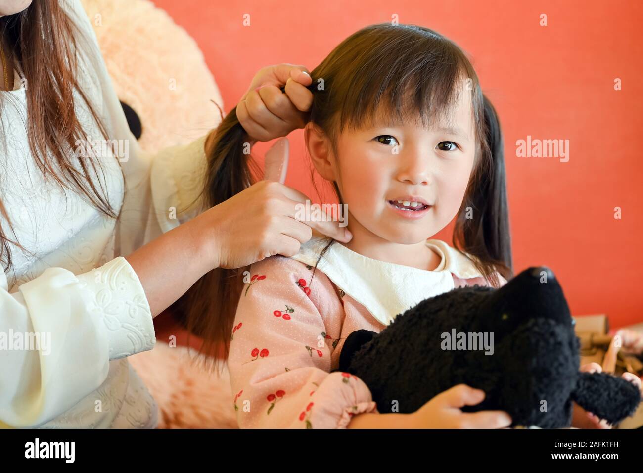 Pettinatura Madre la sua piccola piccola scuola ragazza figlia di capelli con volto sorridente Foto Stock