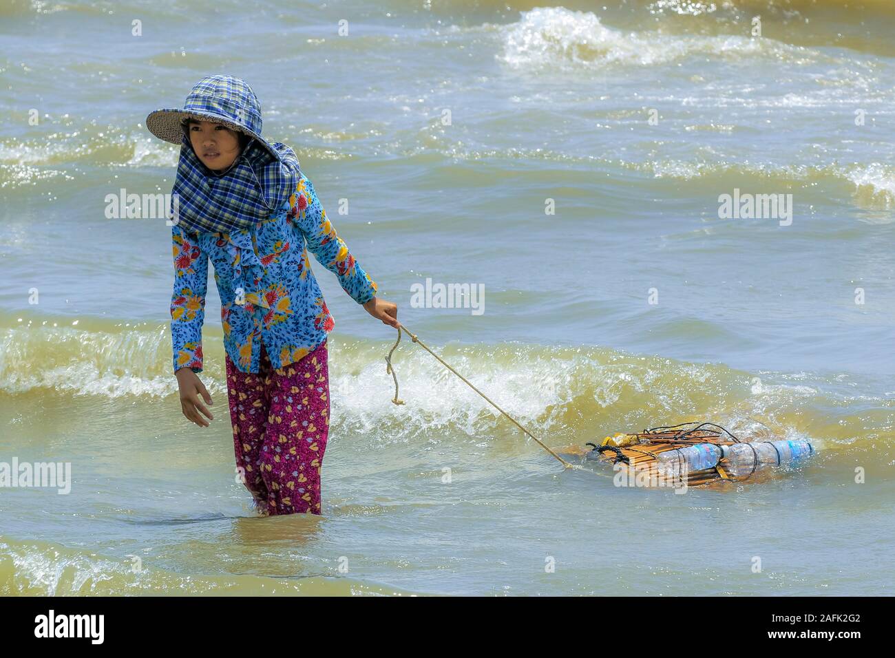 La ragazza di cappello per il sole tirando il granchio cestelli vicino al Mercato di granchio in questo tranquillo il francese ex località di villeggiatura conosciuta per i frutti di mare; Kep, Kep Provincia, Cambogia Foto Stock