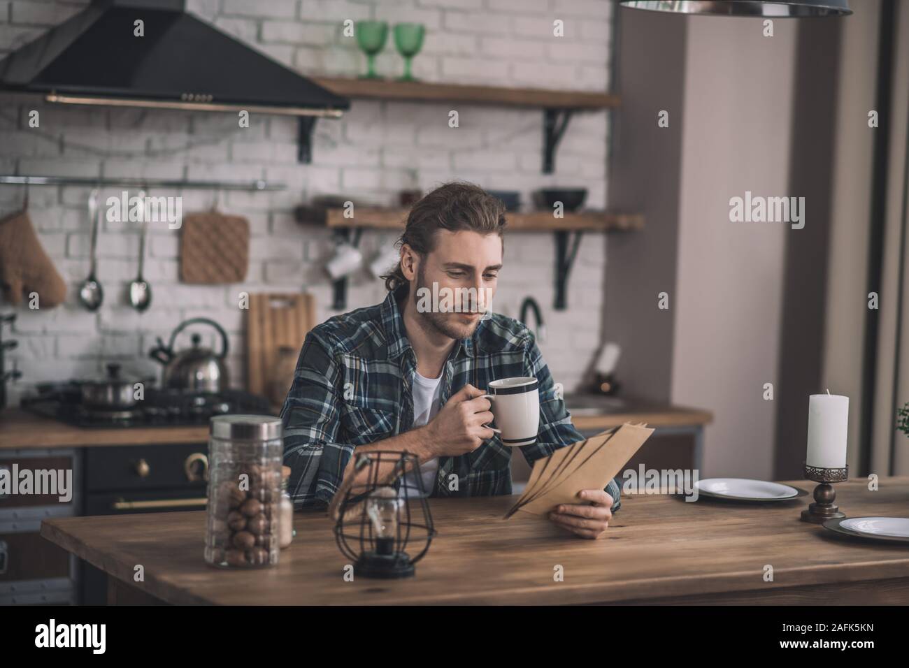 Concentrato giovane la lettura di carte antiche a sua cucina Foto Stock