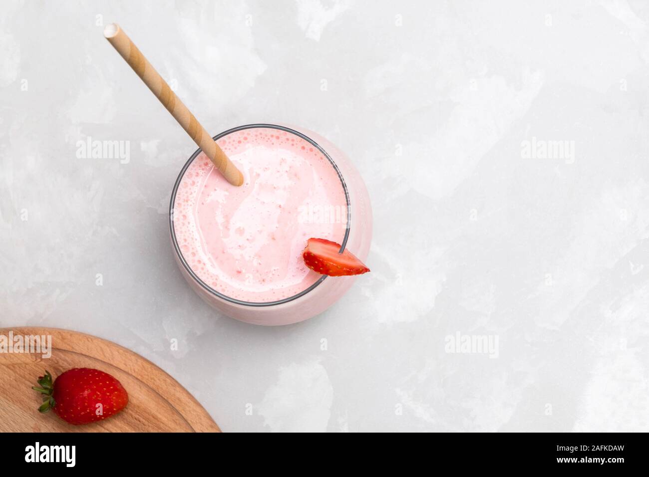 Bevanda indiana Strawberry Lassi in un bicchiere di vetro con carta paglia, Foto Stock