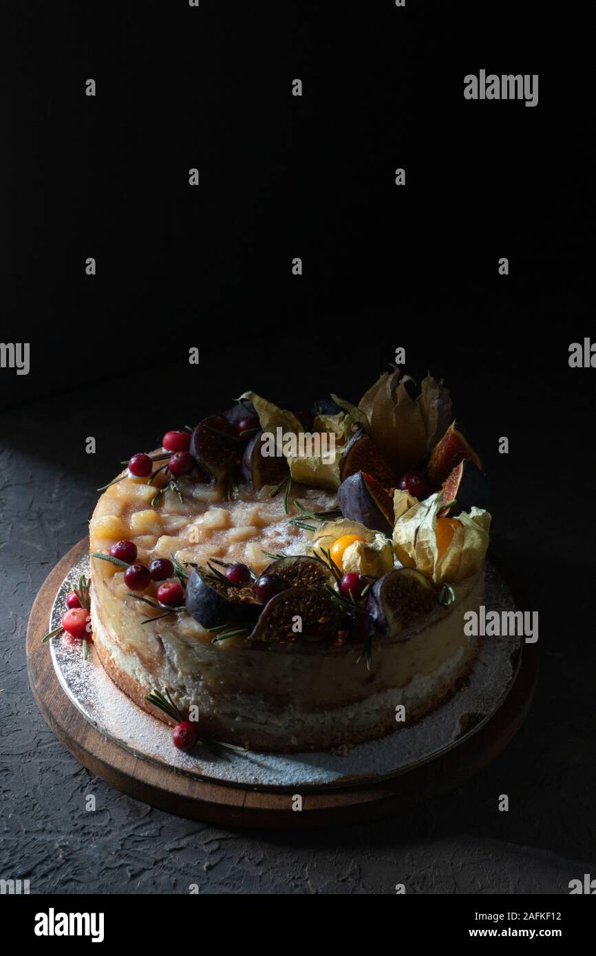 Cheesecake con fichi e physalis su una tavola di legno in verticale Foto Stock