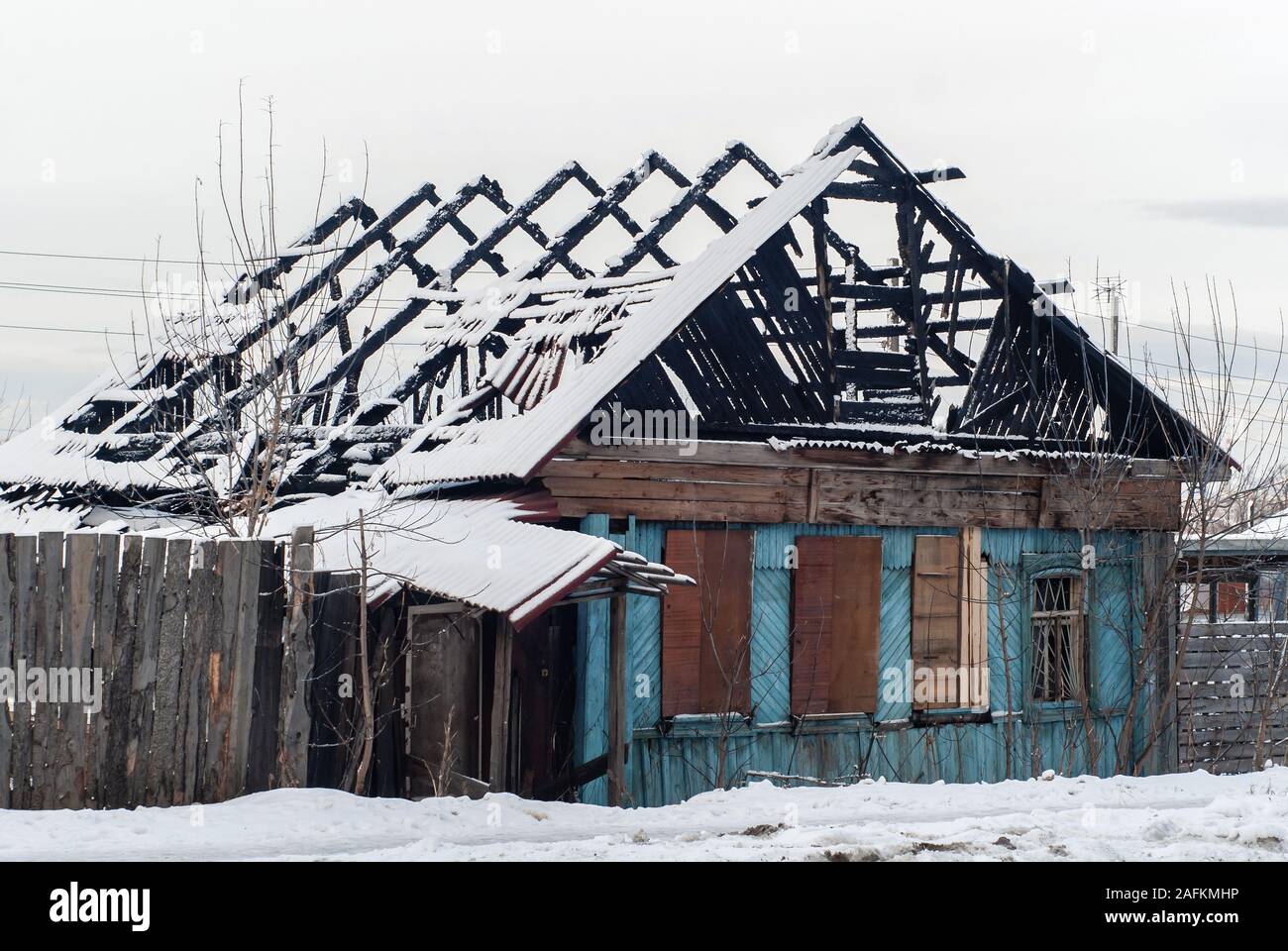 Rovine di un legno bruciato edificio residenziale in un paesaggio innevato Foto Stock