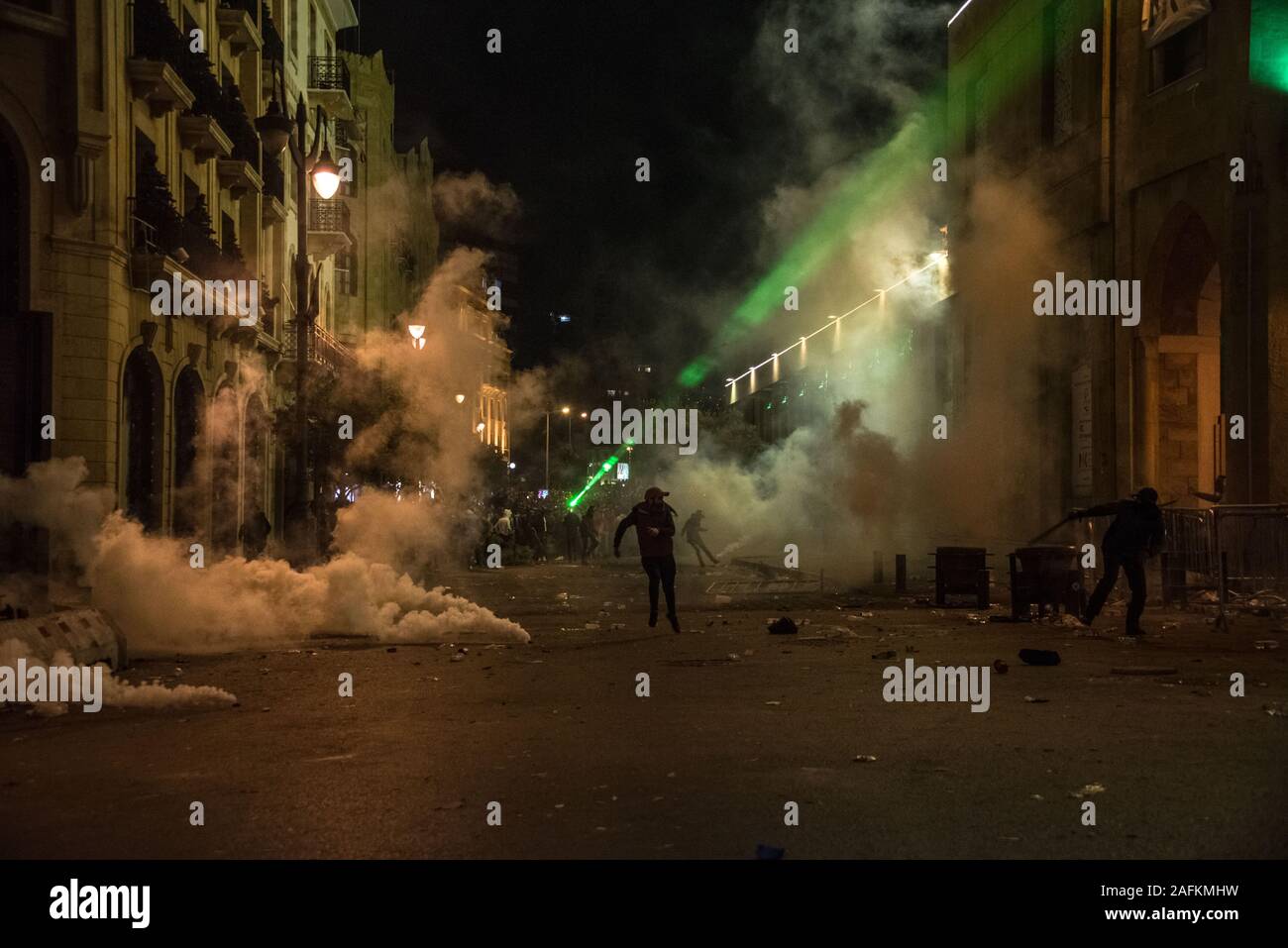 Due manifestanti che corre attraverso i gas lacrimogeni nel centro cittadino di Beirut, dove sono raccolti in decine di migliaia di domenica per esprimere la loro avversione per ciò che sentono di essere eccessiva violenza della polizia. Dopo 2 ore di sostenuta della concia di linee di polizia con fire crackers, pietre, luci laser e bottiglie d'acqua da una minoranza di manifestanti, che poi tirato giù barriere di sicurezza nonostante gli sforzi degli altri manifestanti per formare uno scudo umano, la polizia vendicato, carica i manifestanti e blanketing il quartiere di gas lacrimogeni in mezzo di esecuzione di battaglie che è durato fino alle prime ore del mattino. Elizabeth Fitt Foto Stock