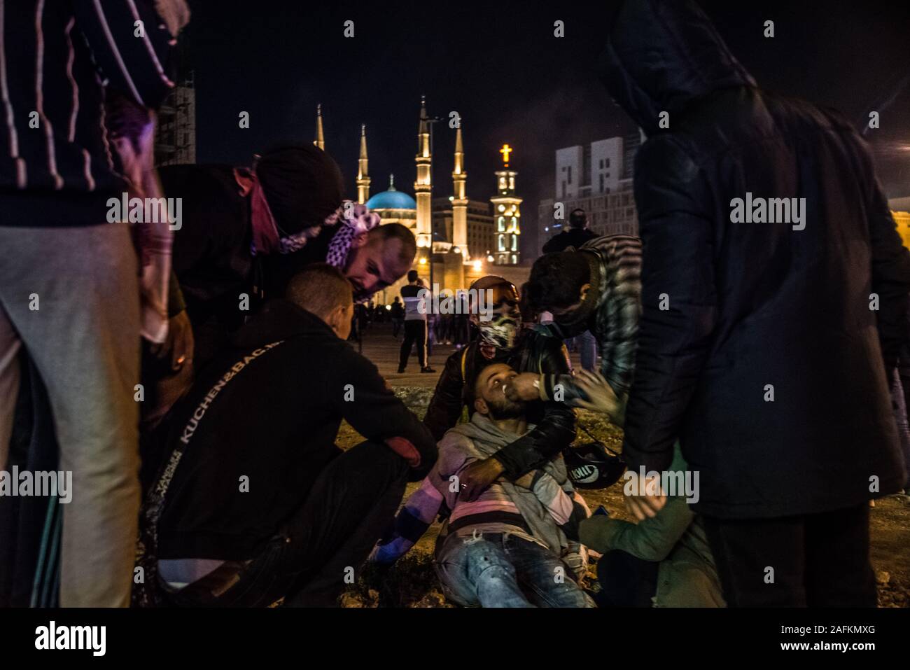 Un manifestante superati dal gas lacrimogeno è aiutato da amici e i passanti. I dimostranti si sono riuniti nel centro cittadino di Beirut la domenica per esprimere la loro avversione per ciò che sentono di essere eccessiva violenza della polizia. Dopo 2 ore di sostenuta della concia di linee di polizia con fire crackers, pietre, luci laser e bottiglie d'acqua da una minoranza di manifestanti, che poi tirato giù barriere di sicurezza nonostante gli sforzi degli altri manifestanti per formare uno scudo umano, la polizia vendicato, carica i manifestanti e blanketing il quartiere di gas lacrimogeni in mezzo di esecuzione di battaglie che è durato fino alle prime ore del mattino. Elizabeth Fitt Foto Stock