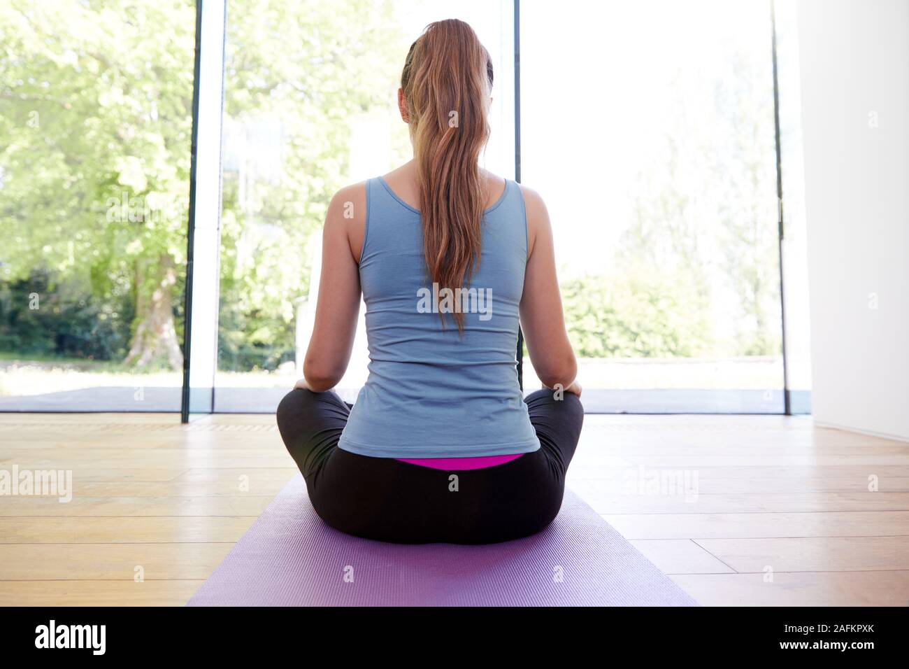 Vista posteriore del giovane donna fare yoga su con pavimenti in legno Studio a casa Foto Stock