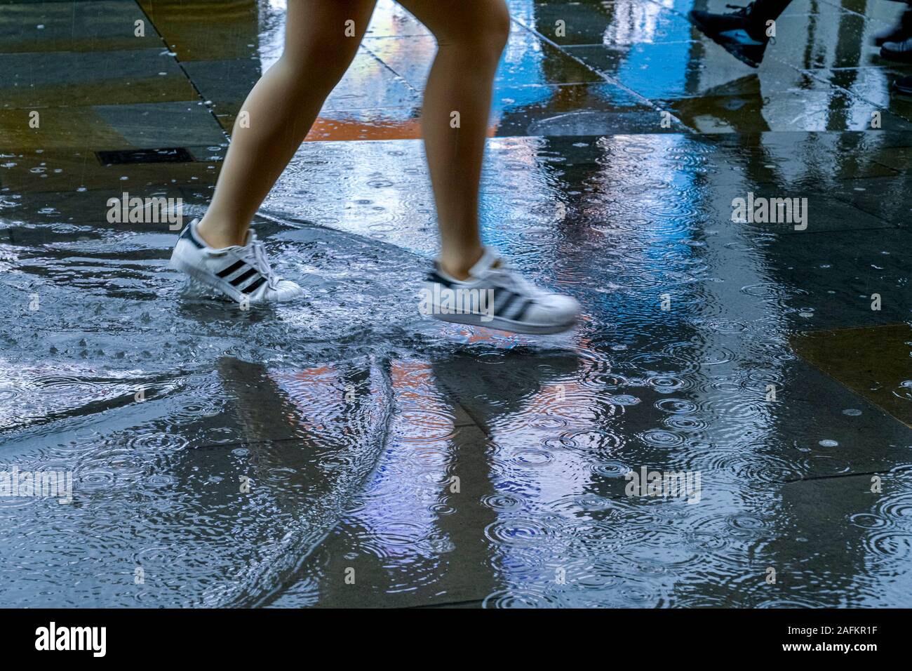 Jogging, scarpe da corsa e piovosa giornata bagnata, pioggia pozzanghera Foto Stock
