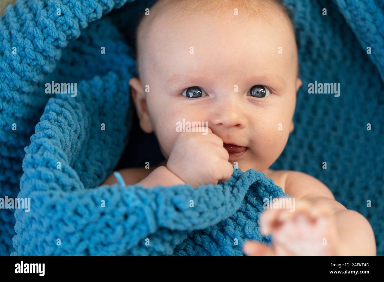 Un simpatico baby boy abbracciando una soffice coltre blu Foto Stock