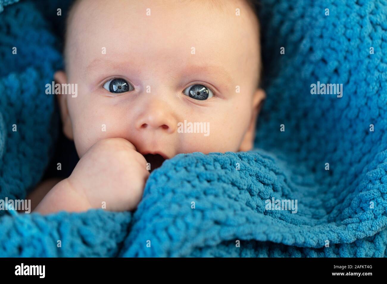 Un simpatico baby boy abbracciando una soffice coltre blu Foto Stock