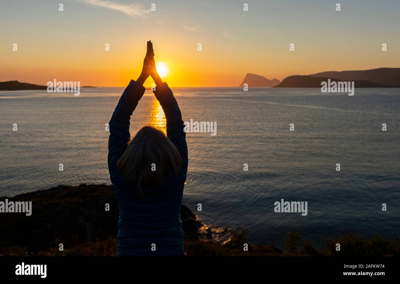 SOMMARØYA, Norvegia - Woman in Yoga asana durante il sole di mezzanotte, Troms, Norvegia settentrionale. Foto Stock
