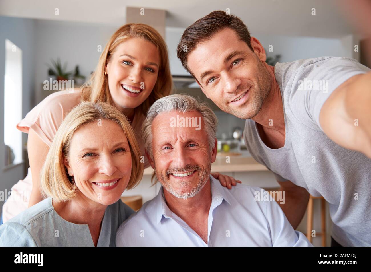 I genitori senior con adulto prole in posa per Selfie a casa Foto Stock