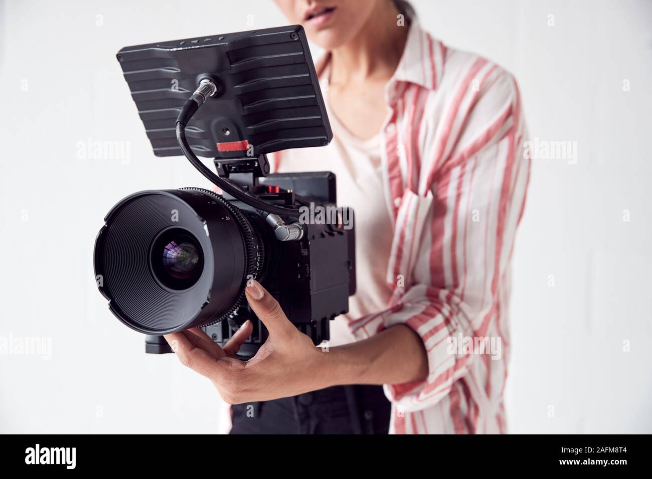 Videografo femmina con riprese con la videocamera filmato In Studio Bianco Foto Stock