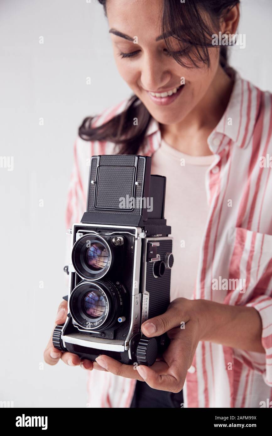 Fotografo femmina con Vintage fotocamera medio formato sulla fotografia di sparare contro il bianco sullo sfondo Studio Foto Stock