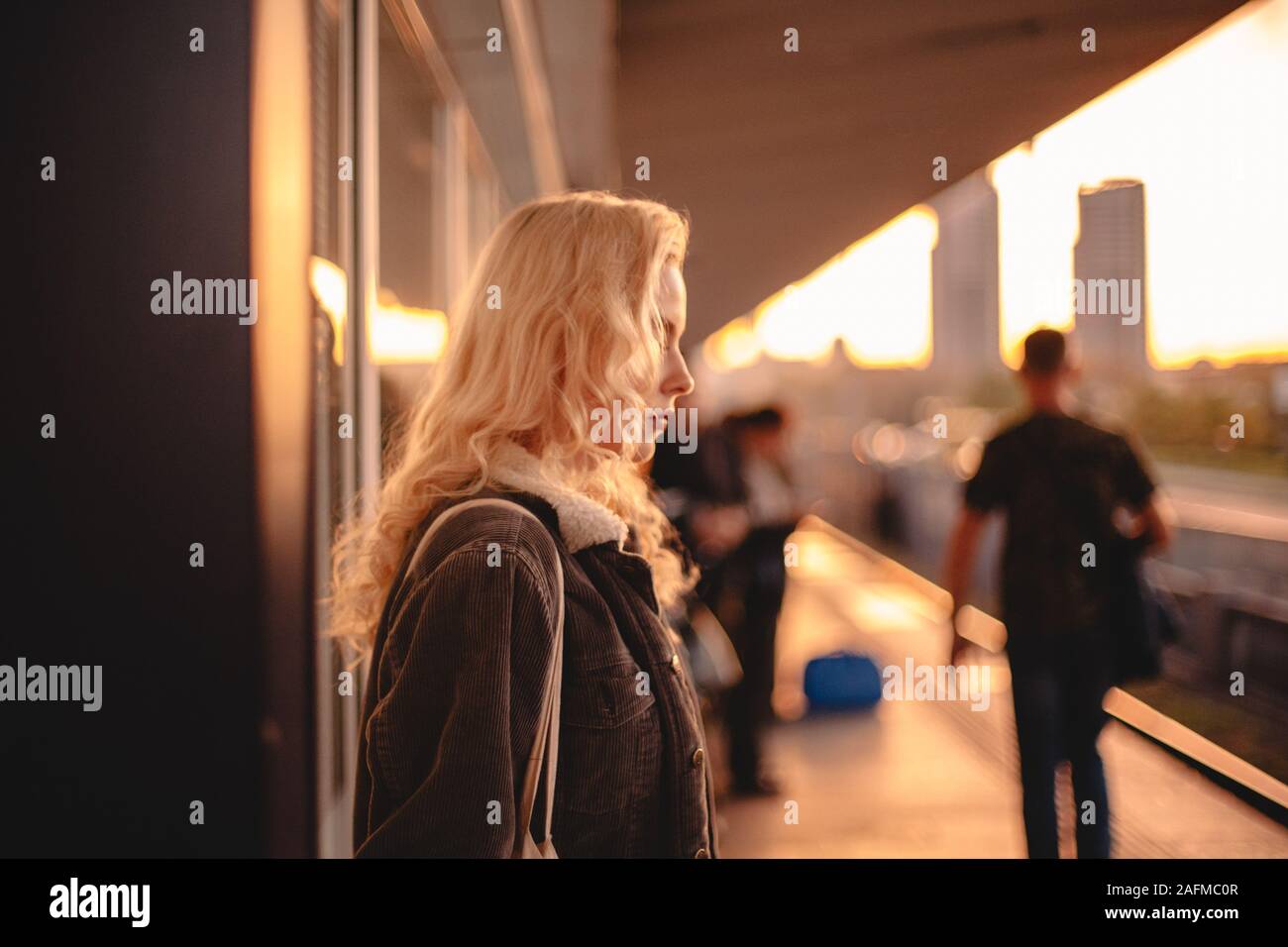Giovane donna con capelli biondi in attesa del treno alla stazione della metropolitana Foto Stock