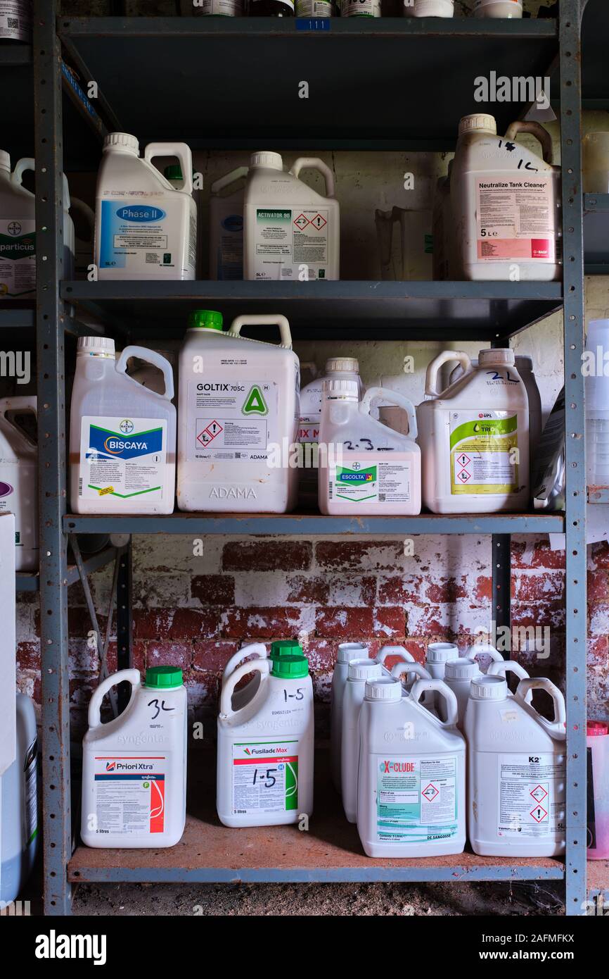 I prodotti agrochimici pesticidi impilati 3 alta su scaffalature metalliche in una fattoria spruzzi di sostanze chimiche store Foto Stock