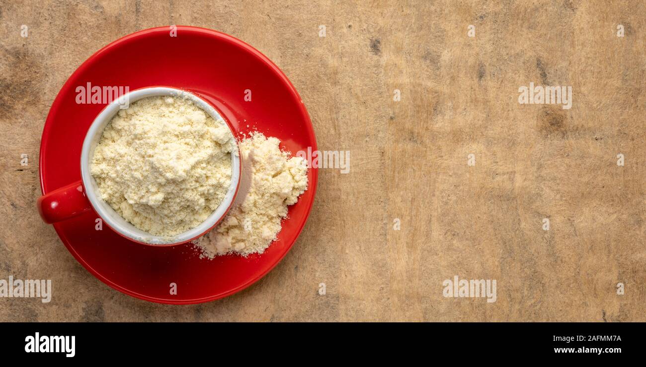 La proteina del siero di latte in polvere in un rosso tazza da caffè contro la trama della carta di corteccia Foto Stock