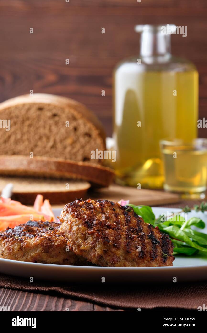 Manzo alla griglia cotoletta con insalata fresca, pane marrone e moonshine su tavola in legno rustico Foto Stock