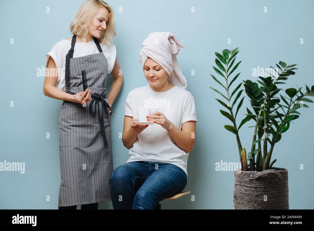 Parrucchiere in chat con il suo cliente, killing time mentre la sbianca dei capelli. Foto Stock