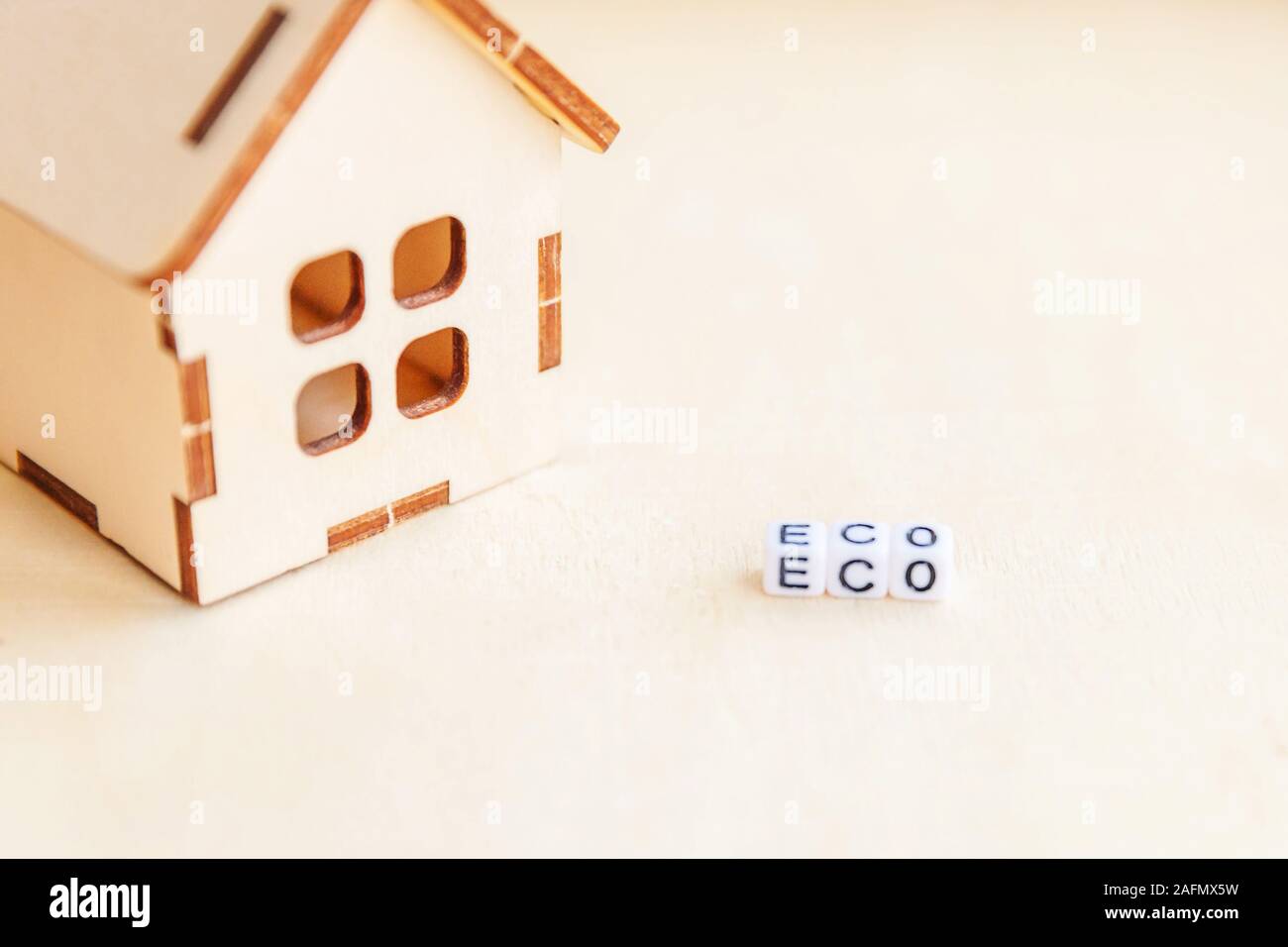 Giocattolo in miniatura Modello di casa con iscrizione ECO lettere parola su uno sfondo di legno. Eco Villaggio abstract sfondo ambientale. Ecologia rifiuti zero responsabilità sociale riciclare bio home concetto Foto Stock