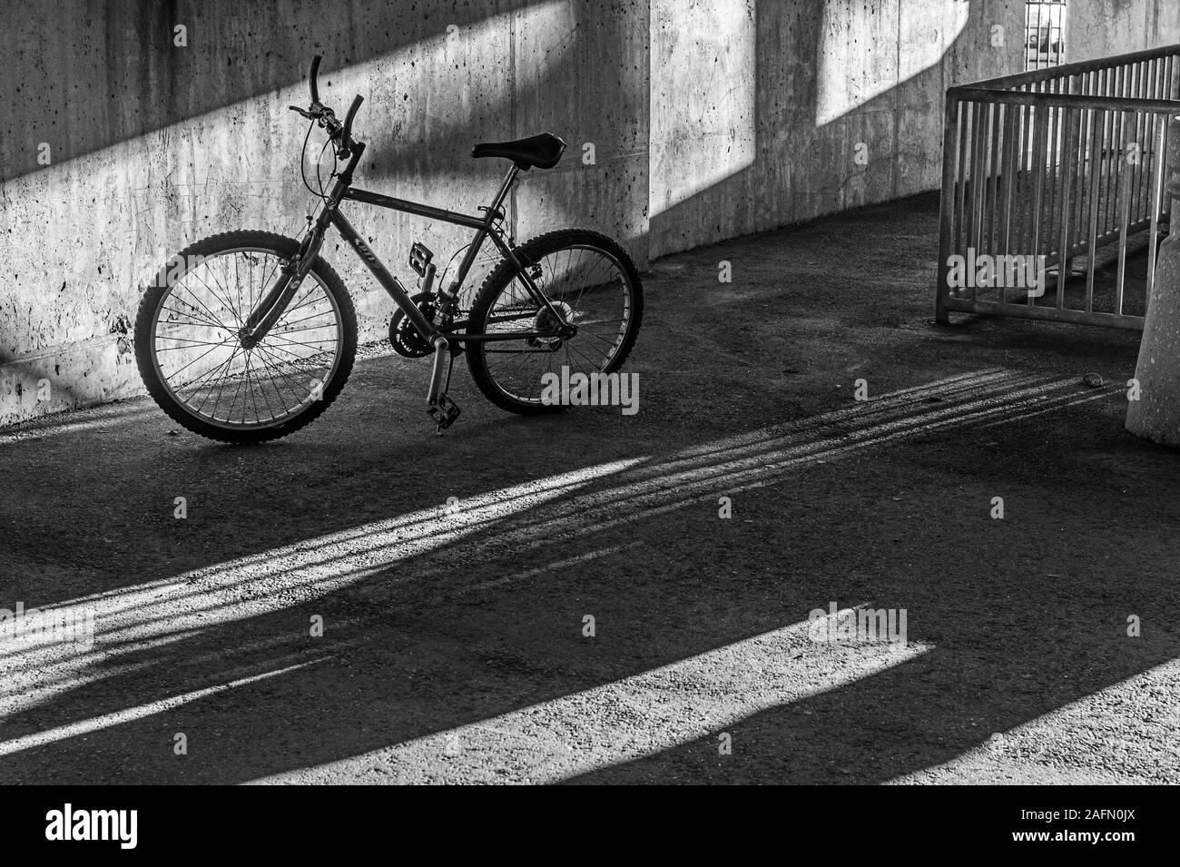 Un bycycle lasciato incustodito nel garage parcheggio con luce e ombre Foto Stock