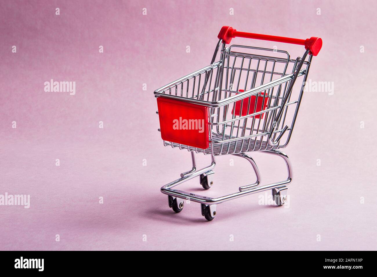 Un carrello della spesa o il trolley su sfondo rosa Foto Stock