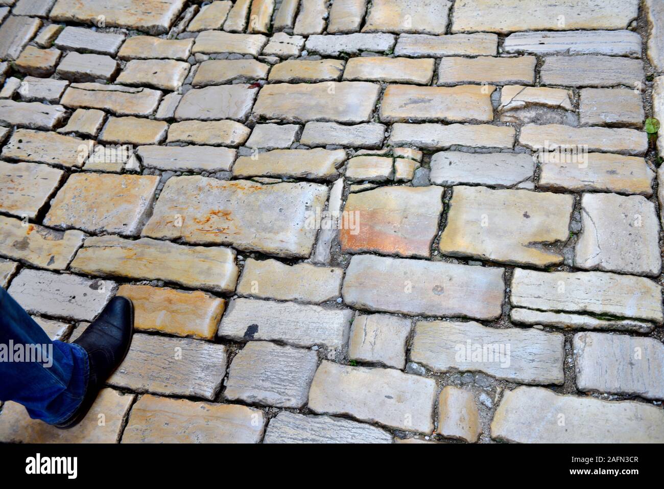 Piede destro avanti sulla pavimentazione in pietra Foto Stock