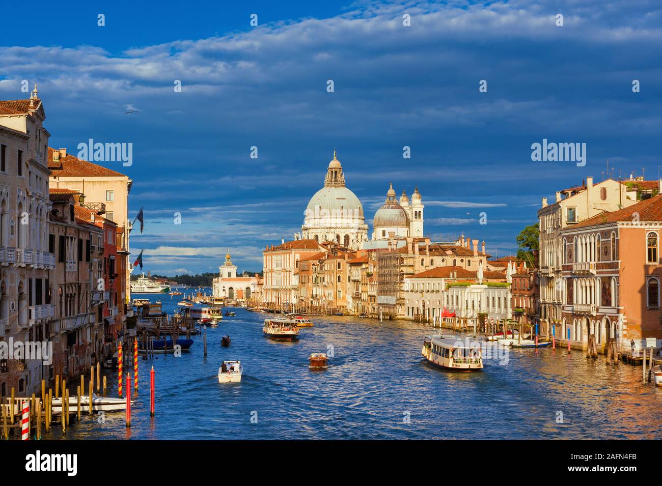 Il trasporto pubblico e il turismo a Venezia. Gondole, traghetto, acqua taxi e autobus attraversare il Canal Grande vicino la mitica salutate Basilica Foto Stock