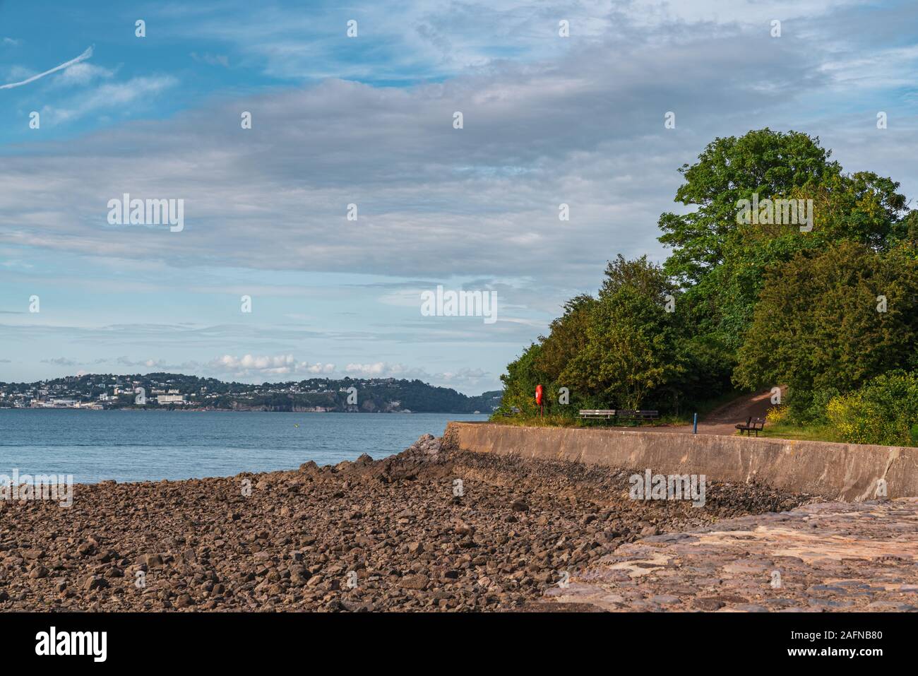 Un banco vicino alla spiaggia in Broadsands, Torbay, England, Regno Unito - con Torquay in background Foto Stock