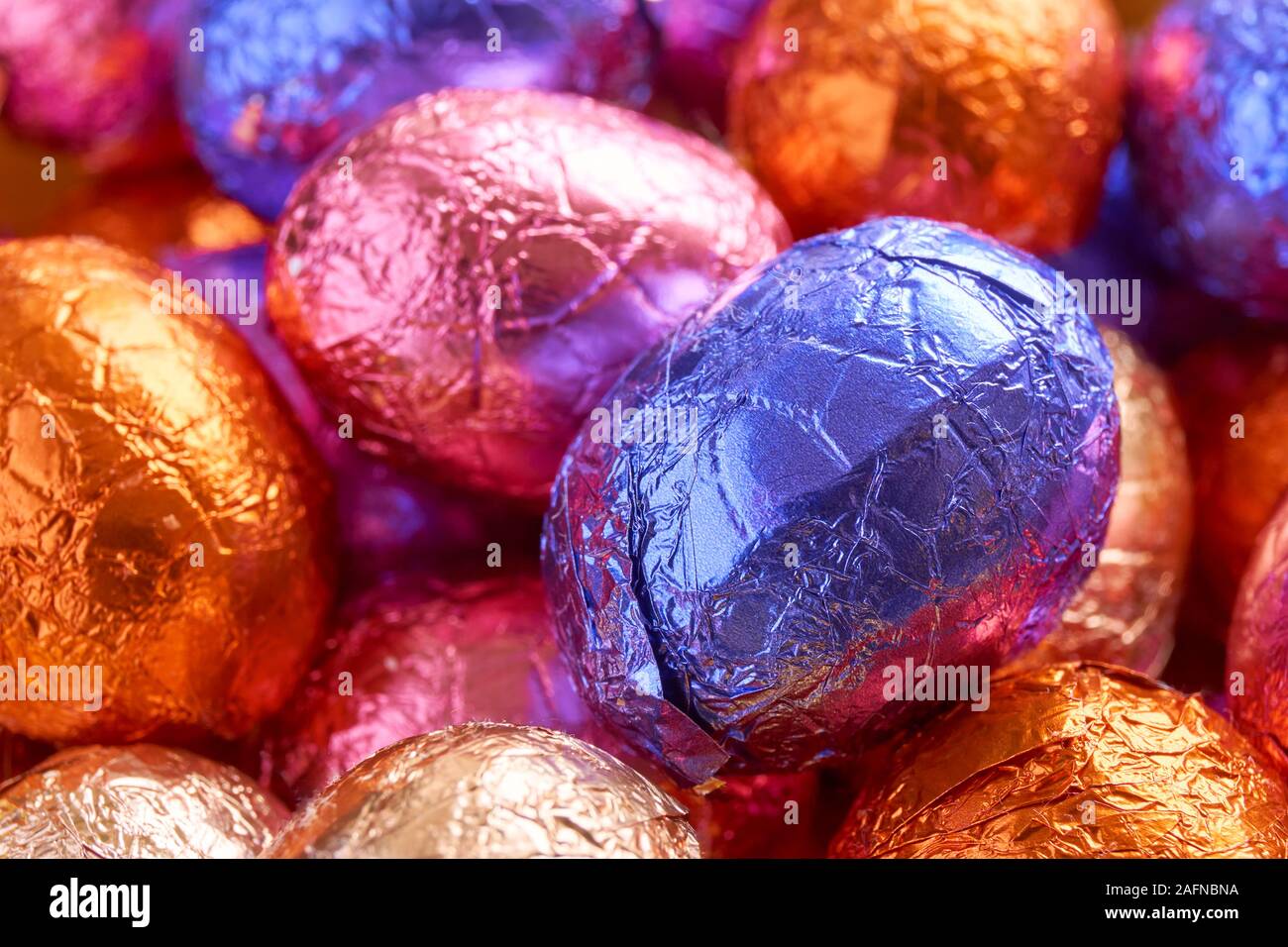 Molte uova di pasqua di cioccolato avvolto in blu, viola, arancione, rosa e lamina dorata wrap Foto Stock