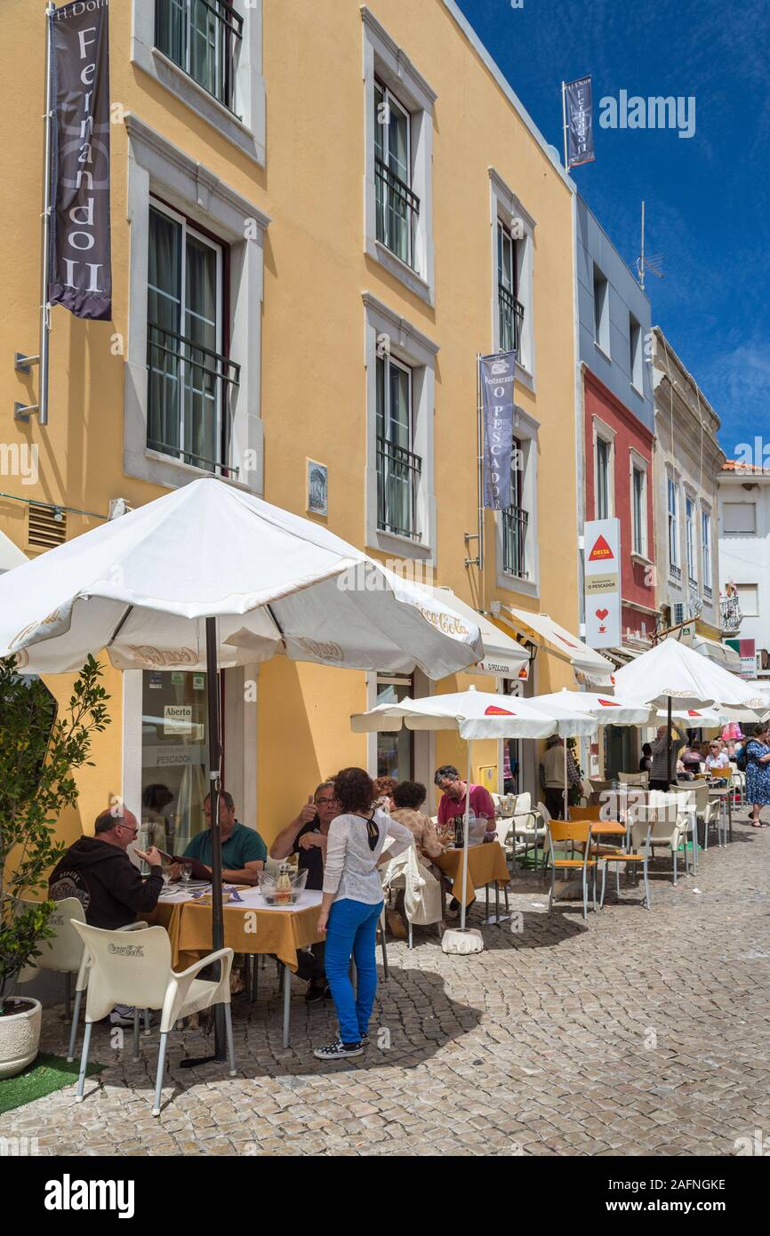 La gente seduta al ristorante i tavoli e le sedie in strada, Loule, Algarve, PORTOGALLO Foto Stock