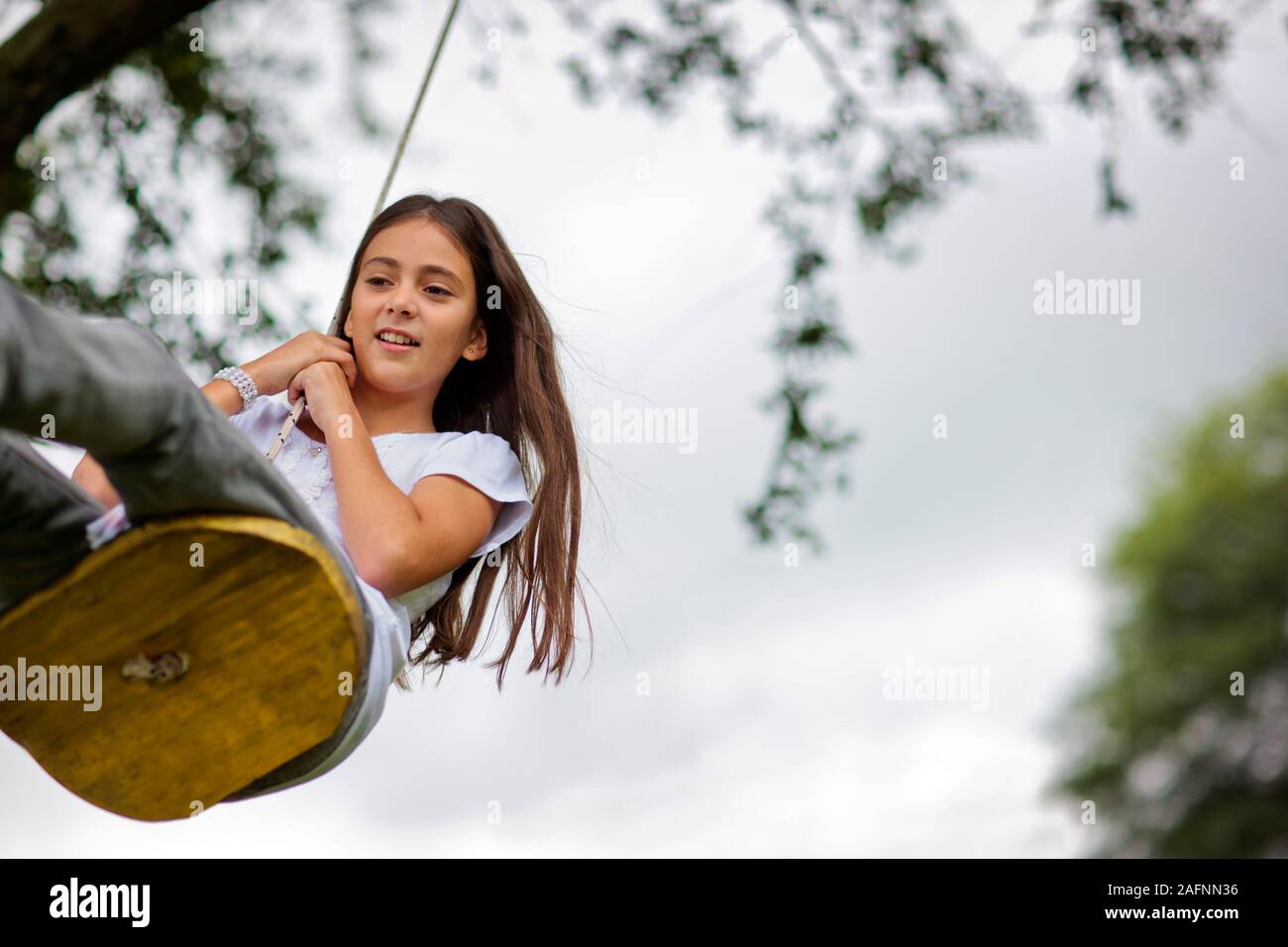 Ragazza oscillare su albero oscillante. Foto Stock