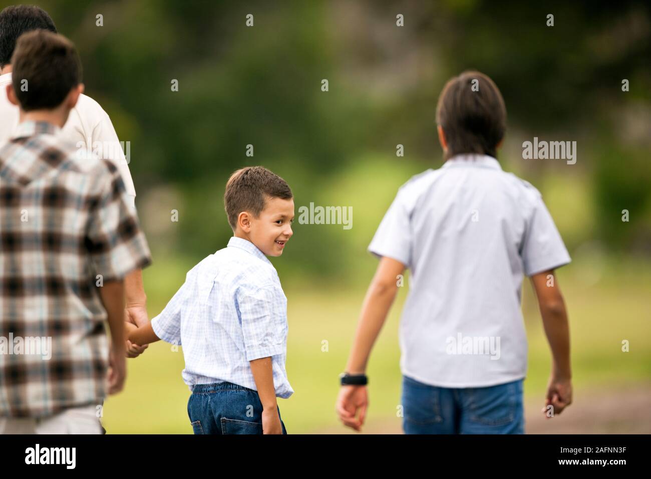 Tre ragazzi a piedi con il loro padre. Foto Stock