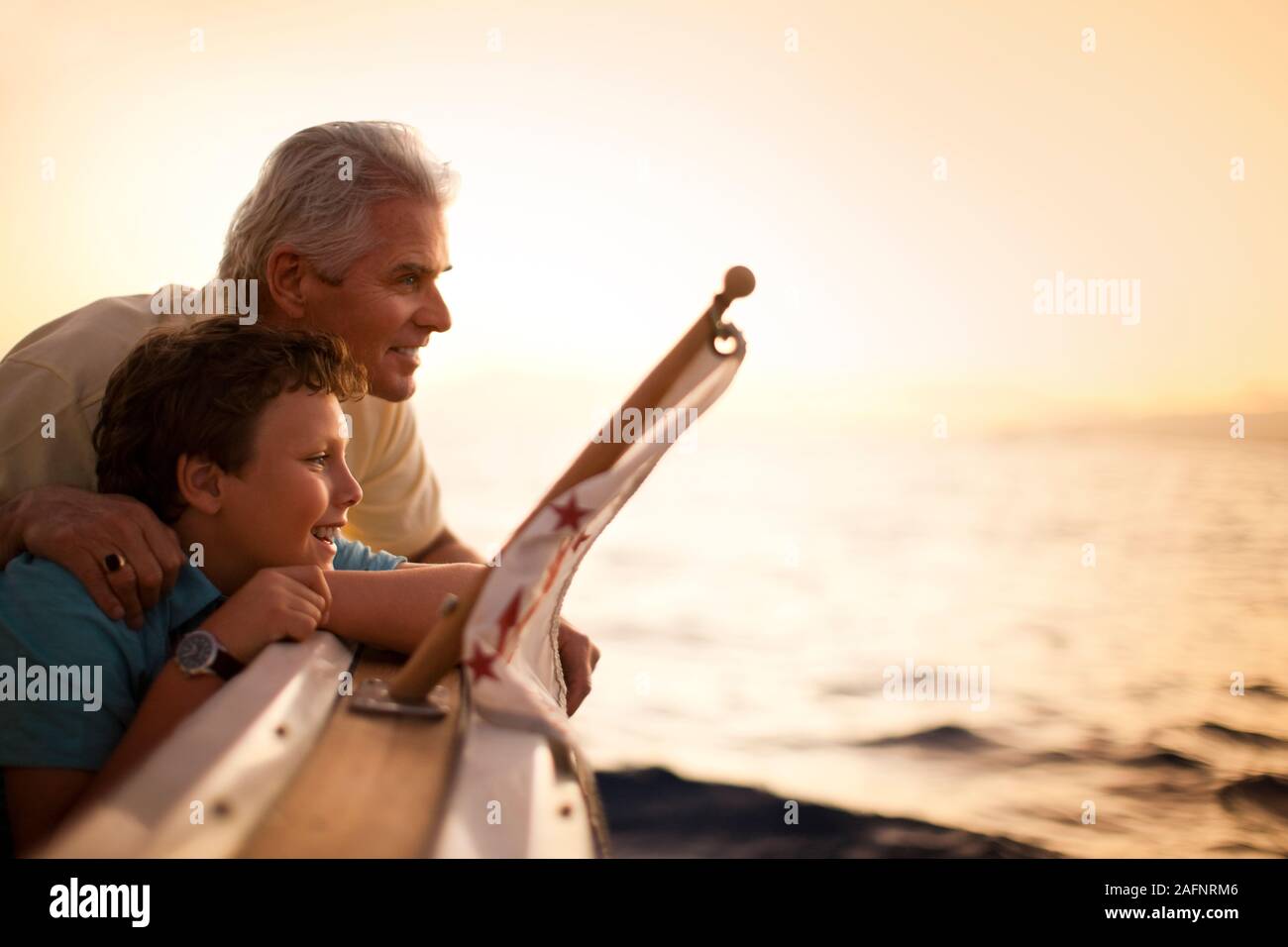 Uomo maturo e suo figlio guardando il tramonto dal lato della barca. Foto Stock