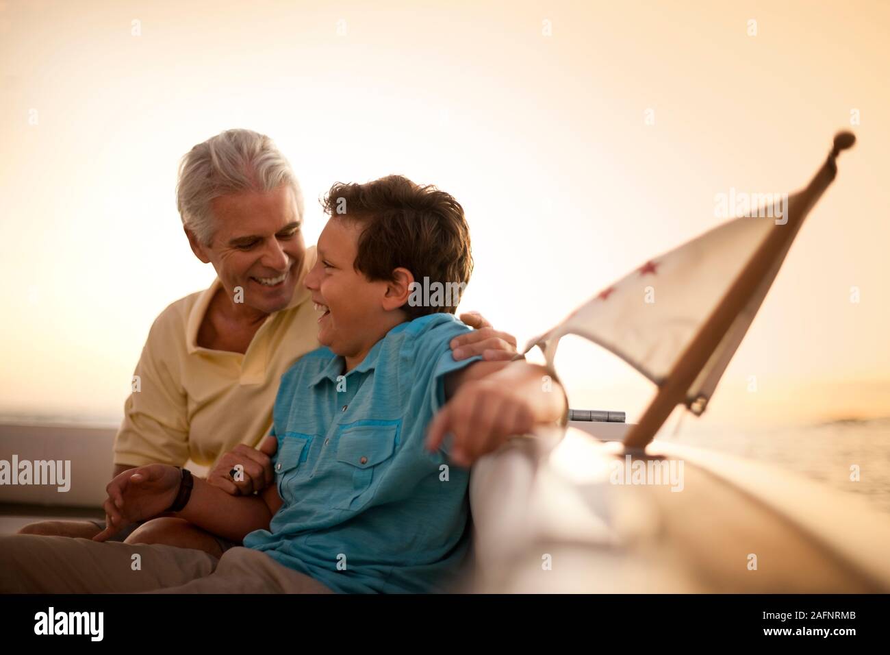 Padre e figlio ridere insieme in barca al tramonto. Foto Stock