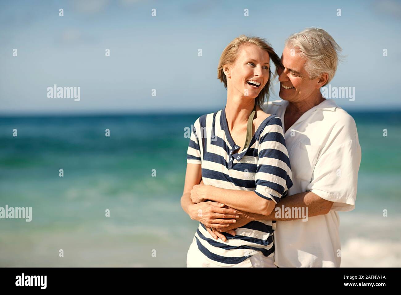 Uomo maturo abbracciando la moglie sulla spiaggia. Foto Stock